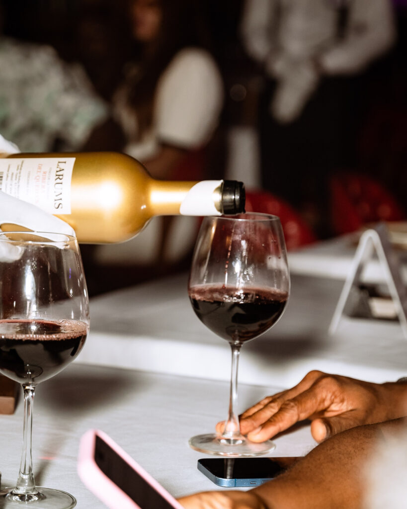 An image of a waiter pouring red wine into a wine glass