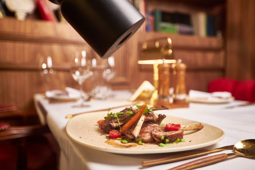 A waiter seasoning the steak with a blower